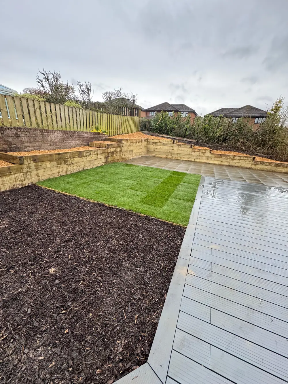 Tiered garden with grey paving, decking, new lawn and golden gravel beds
