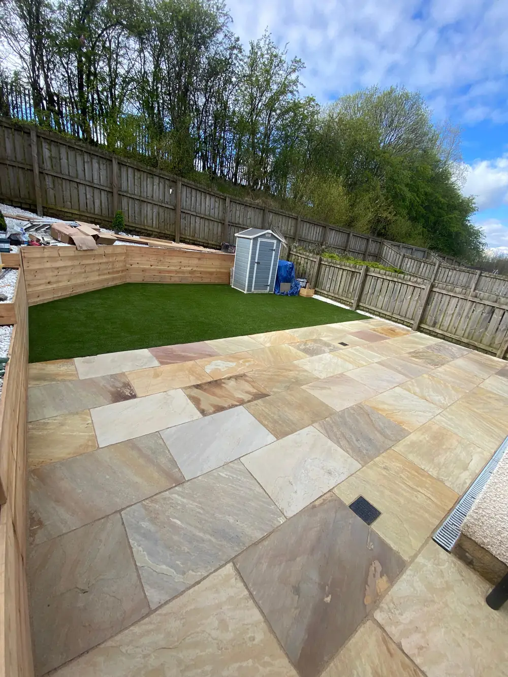 Sandstone patio, artificial grass and sleeper retaining walls with white gravel