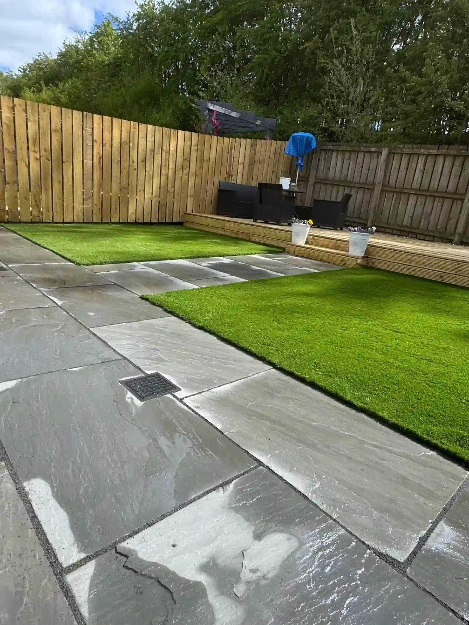 Large slate patio with artificial grass, raised decking area and new fencing