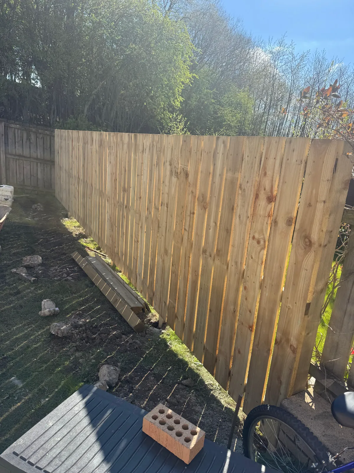 Hit-and-miss timber fence being installed along a garden boundary