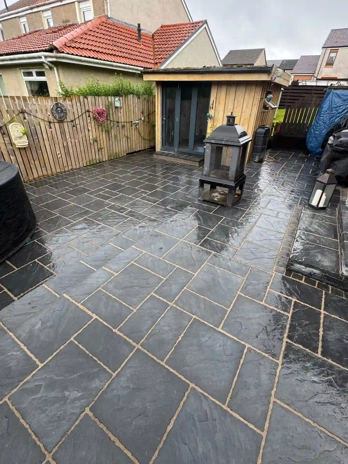 Large dark slate patio with shed and seating area
