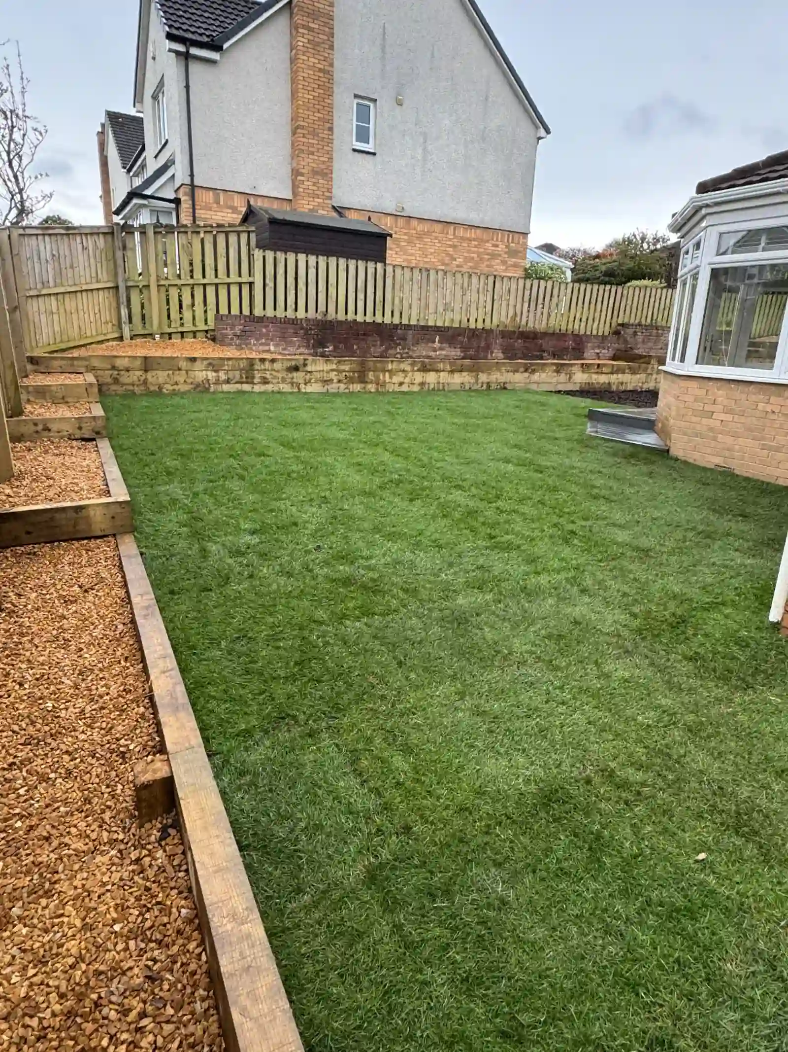 New lawn with sleeper retaining walls, golden gravel path and fencing