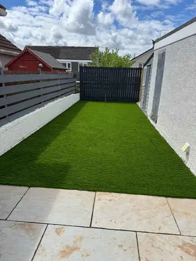 Artificial lawn with painted brick wall and slate fence