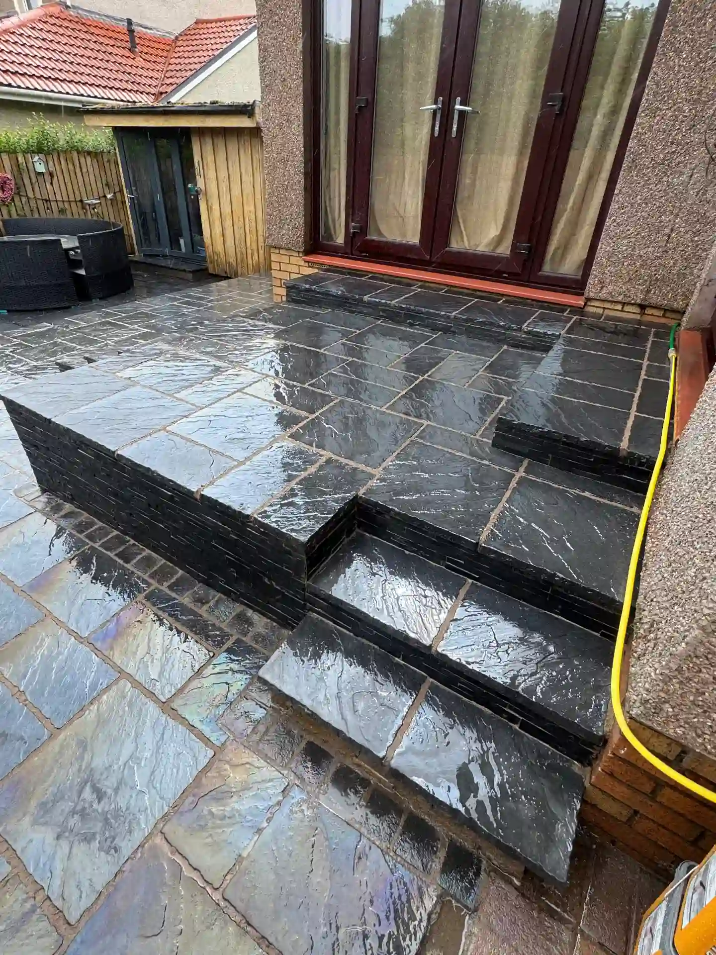 Black slate patio with steps and raised sleeper beds