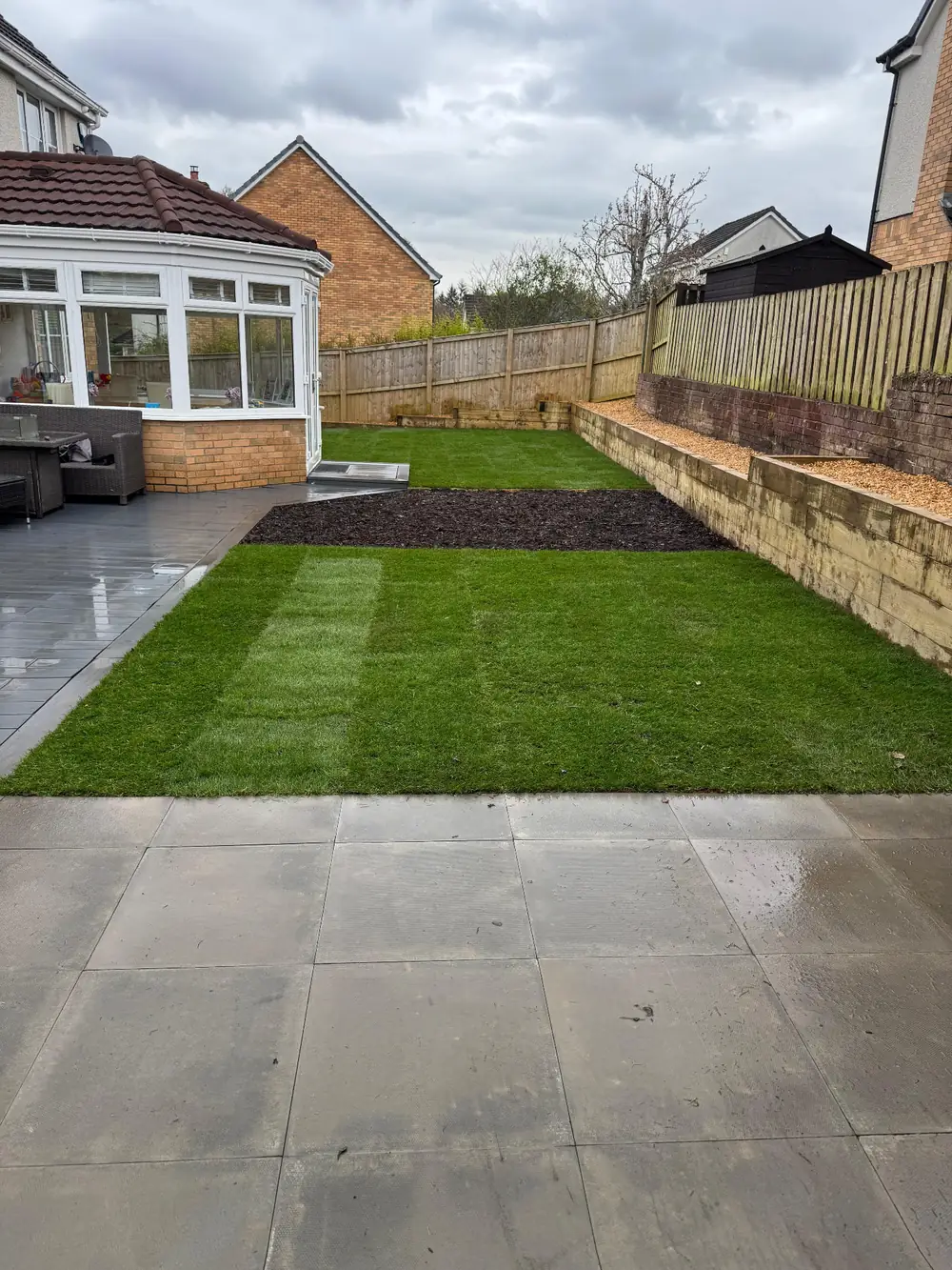 Garden with new lawn, bark beds, grey paving and sleeper retaining walls