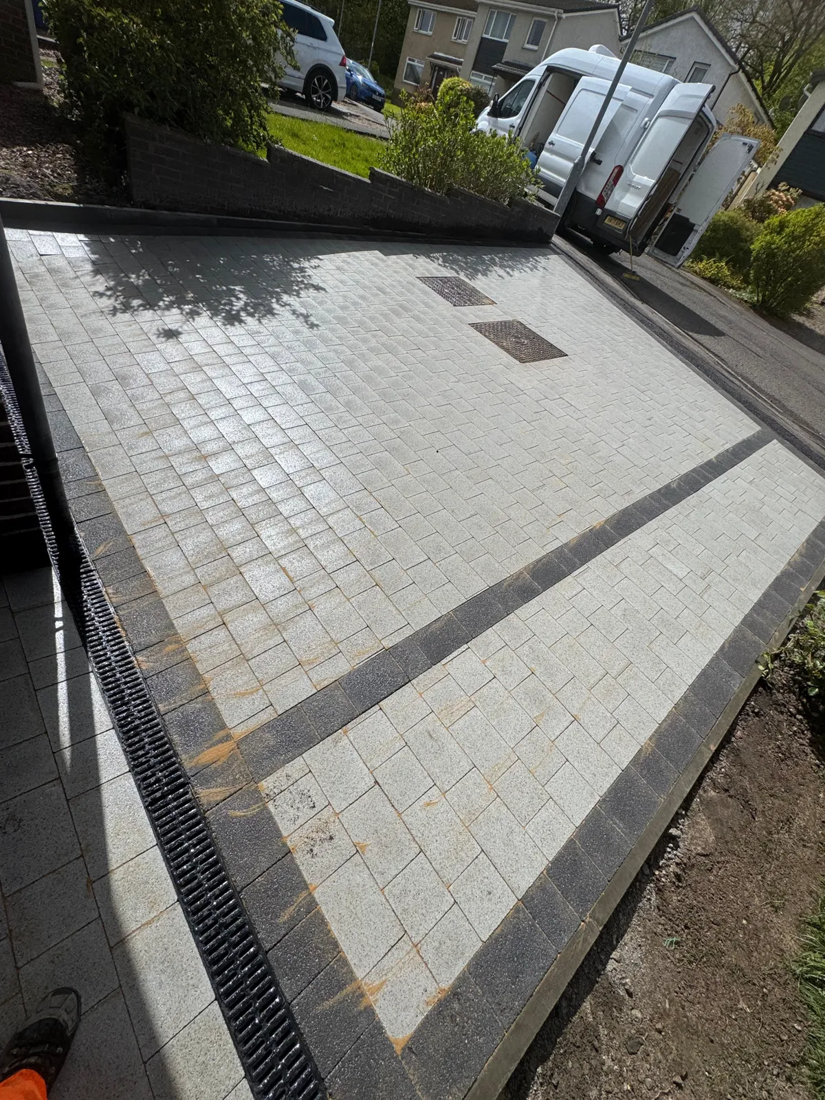 Silver-grey block paved driveway with charcoal bands and channel drain