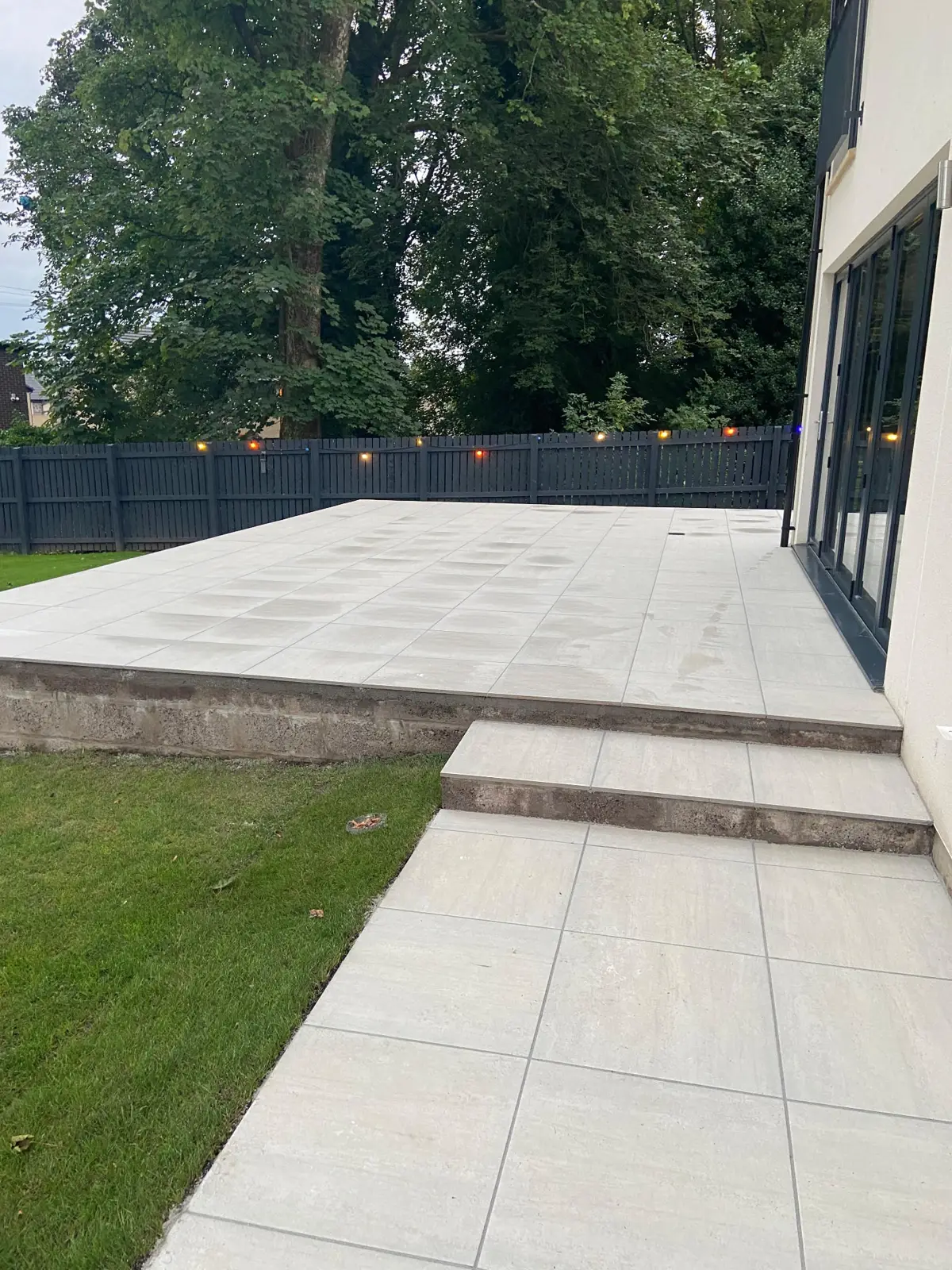 Raised porcelain patio with steps and fence lighting