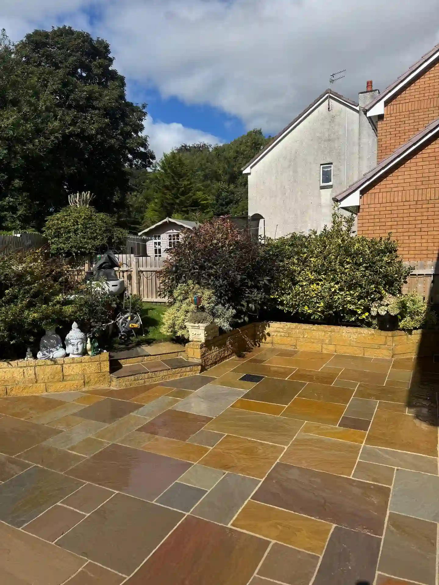 Indian sandstone patio with raised beds and steps to the garden