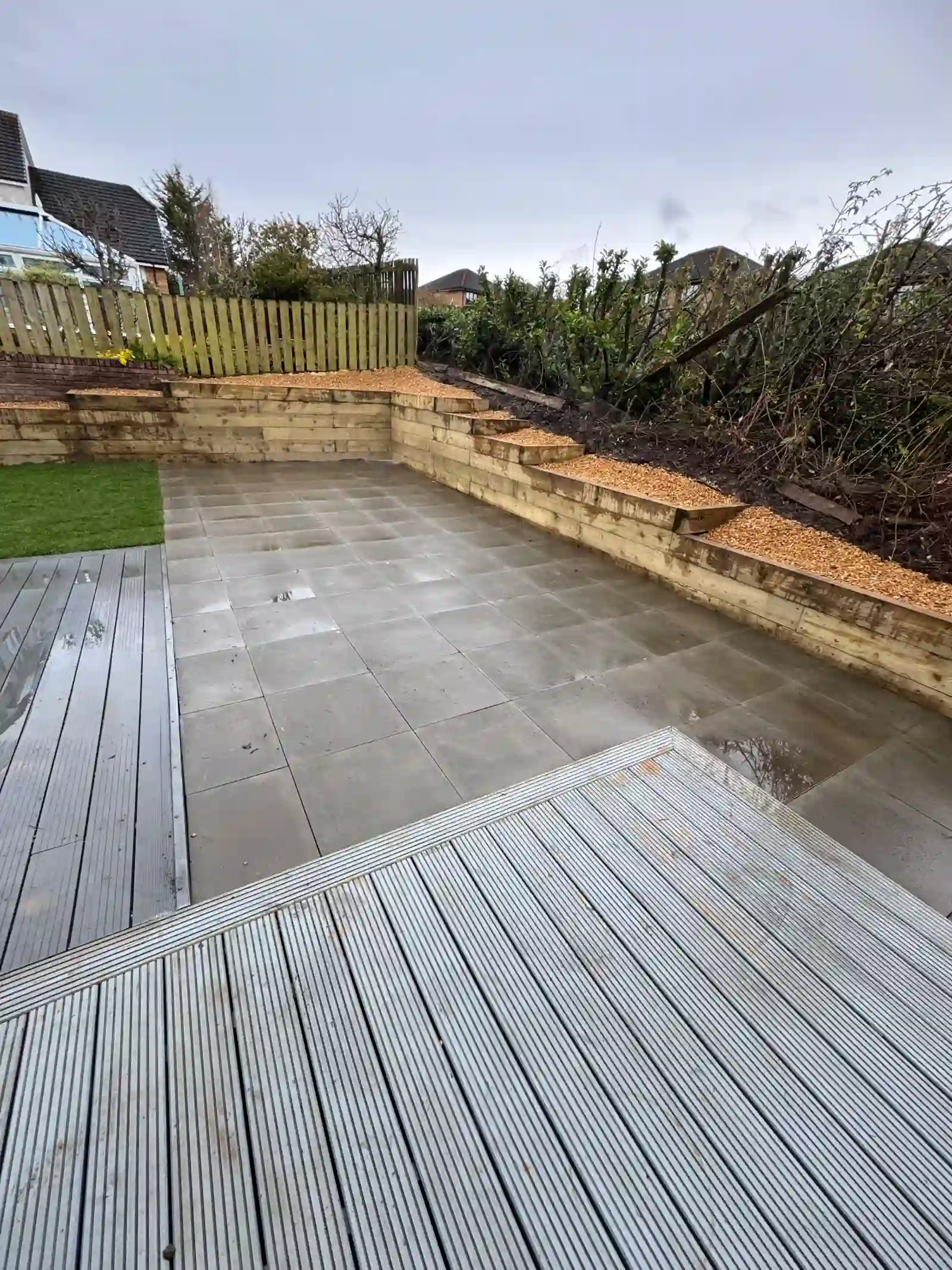 Slate patio with composite decking, sleeper raised beds and artificial grass
