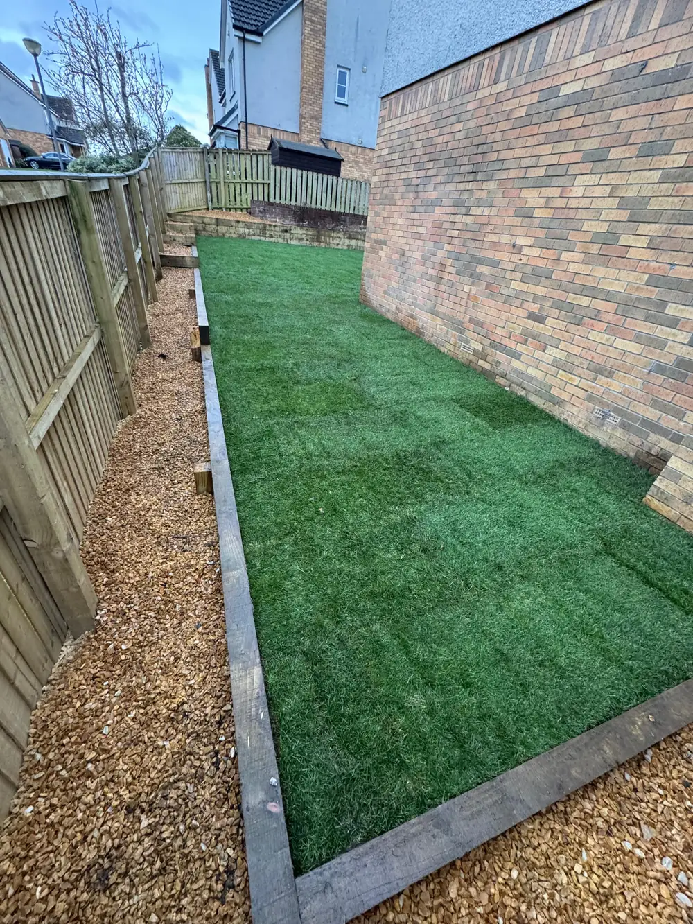 New lawn and golden gravel border alongside the house