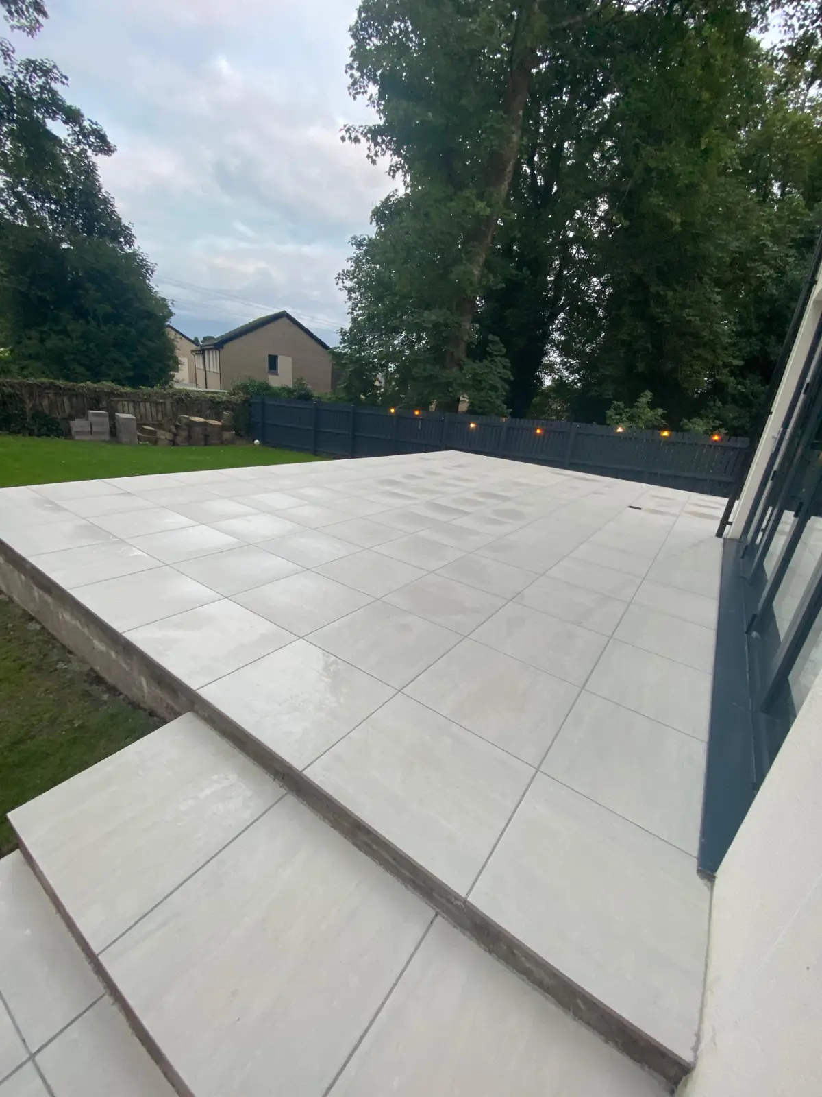 Large raised porcelain patio with lawn